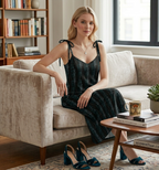Woman in a black dress sitting on a beige sofa in a cozy living room.