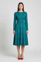 Woman wearing a teal dress with long sleeves on a white background