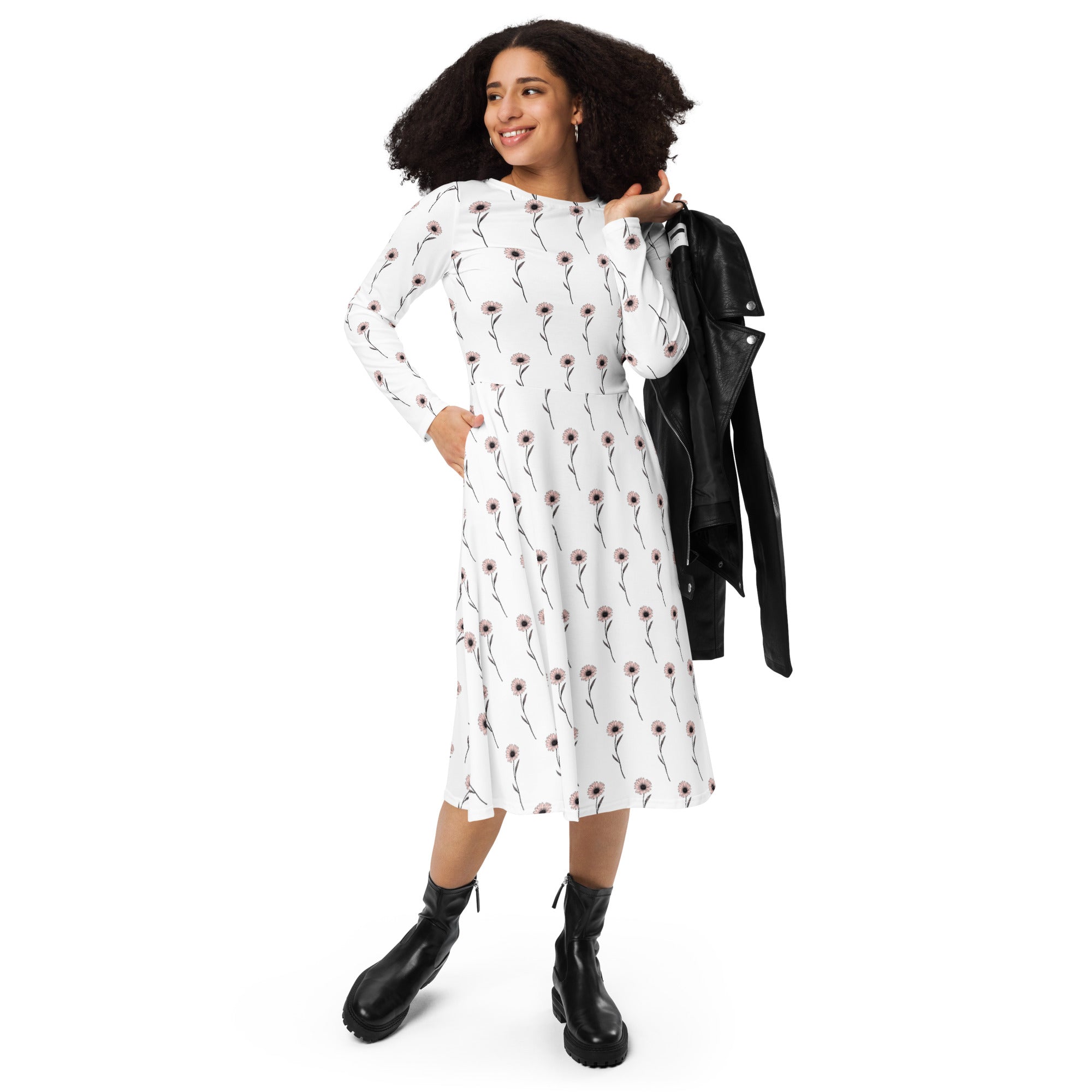 Woman wearing a white dress with a floral pattern, holding a black jacket on a white background