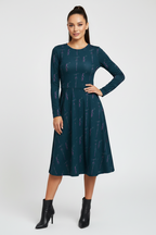 Woman wearing a dark green dress with a pattern on a white background
