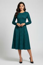 A woman modeling a long-sleeve teal green midi dress with a subtle jacquard pattern, standing against a light gray studio background.