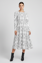 Woman modelling an APPARELHUE white patterned midi dress paired with high-heeled black leather ankle boots.