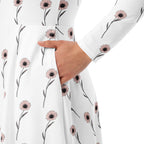 Close-up of a white fabric with pink floral patterns, held by a hand.