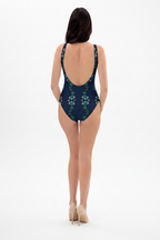 Woman wearing a dark green swimsuit with floral patterns on a white background