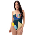 A woman smiling in a dark one-piece swimsuit with a colorful geometric abstract print.