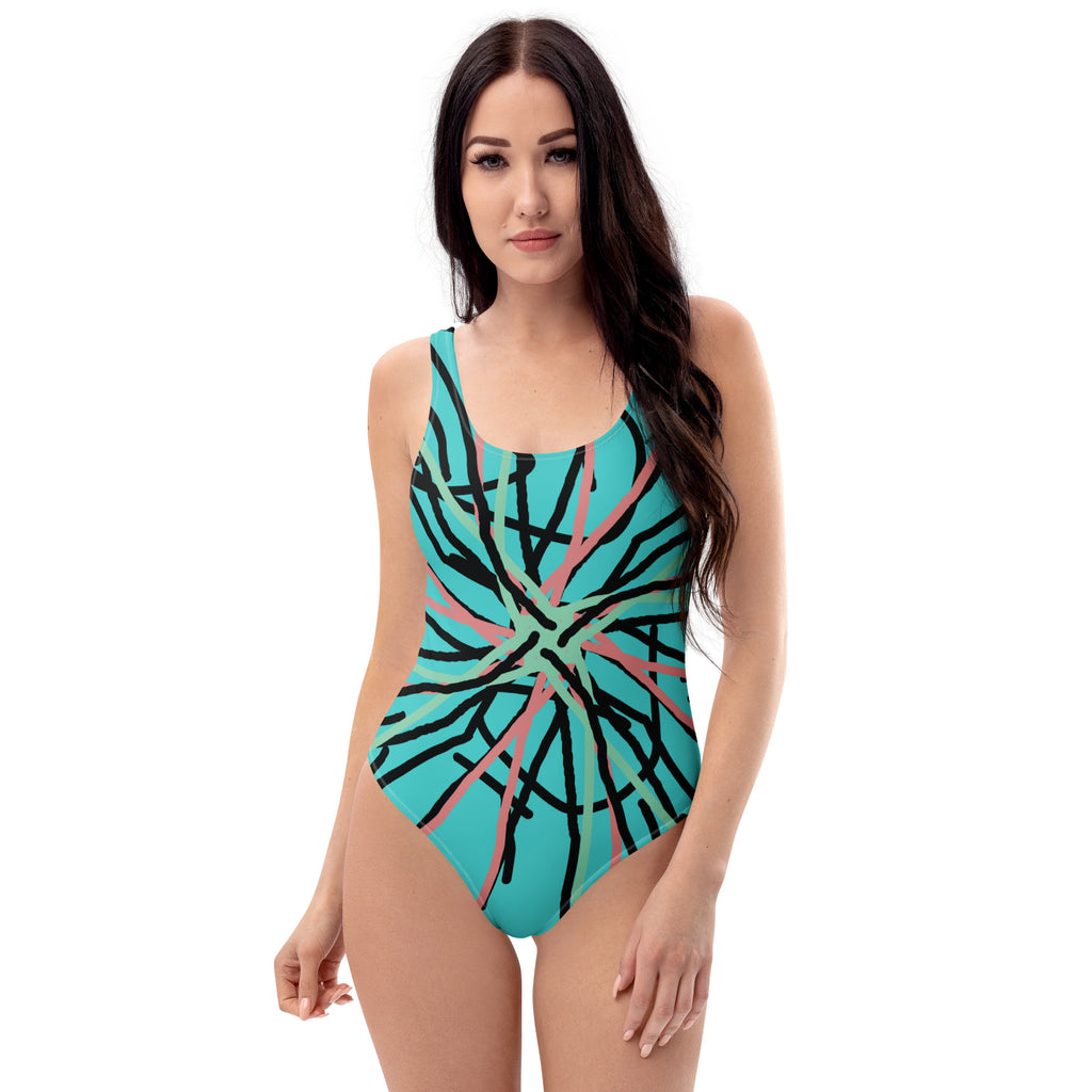 A woman smiling in a light blue one-piece swimsuit with a black, pink, and green abstract line print.