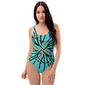 A woman smiling in a light blue one-piece swimsuit with a black, pink, and green abstract line print.