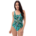 A woman smiling in a light blue one-piece swimsuit with a black, pink, and green abstract line print.