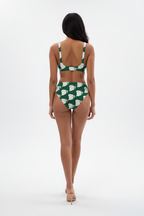 Person wearing a green and white floral bikini on a white background