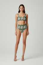 Woman wearing a green bikini with white patterns on a light gray background