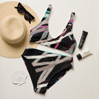 Patterned swimsuit with sun hat, sunglasses, and sunscreen on a light background