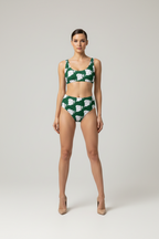 Woman wearing a green and white patterned bikini set on a plain background