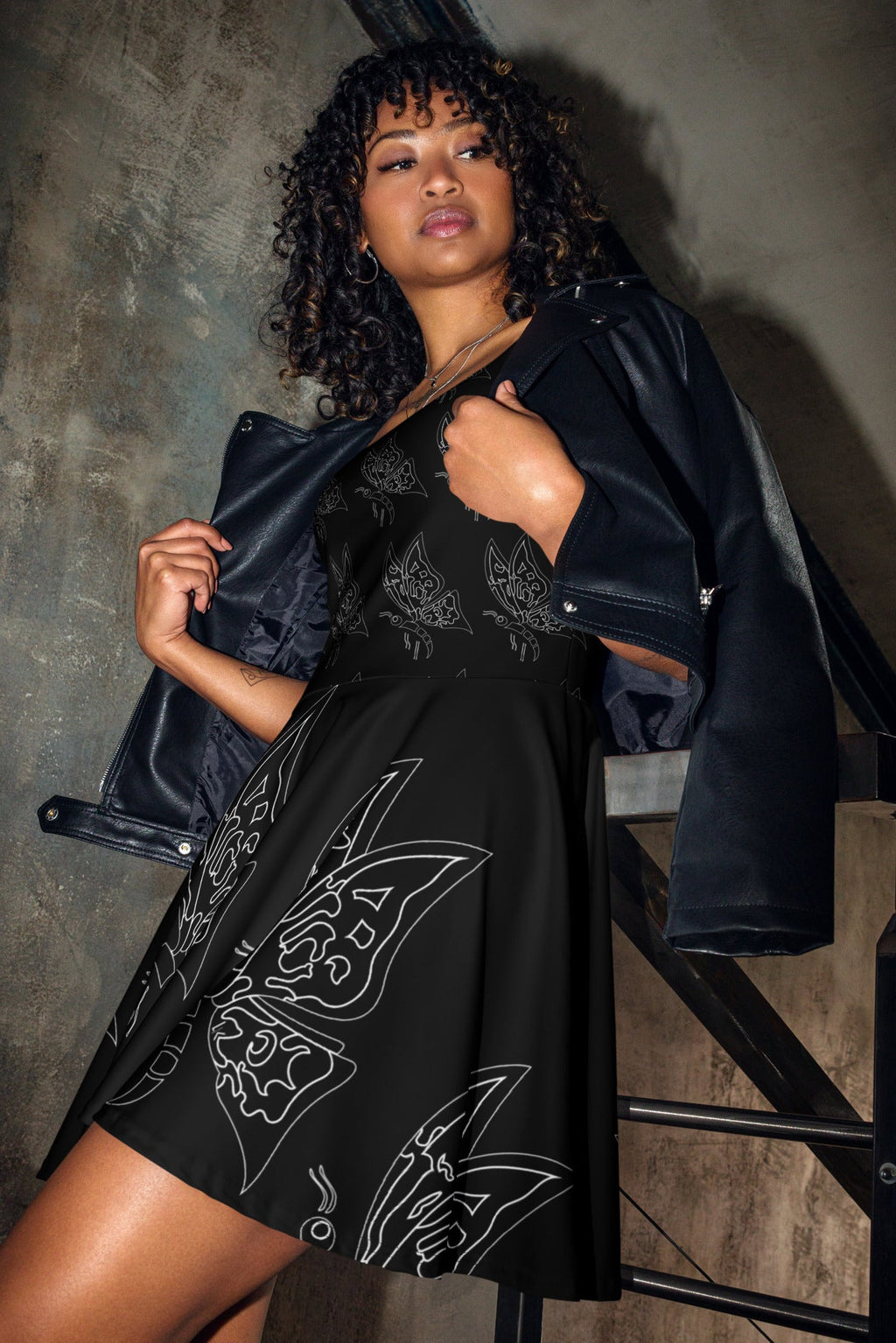 Model wearing a sleeveless black skater dress featuring an all-over white line art butterfly print from Apparelhue.