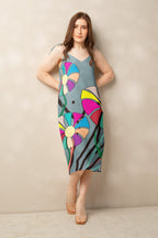 Front view of a woman modeling a v-neck, sleeveless midi dress in soft gray with large, multi-colored flower prints.