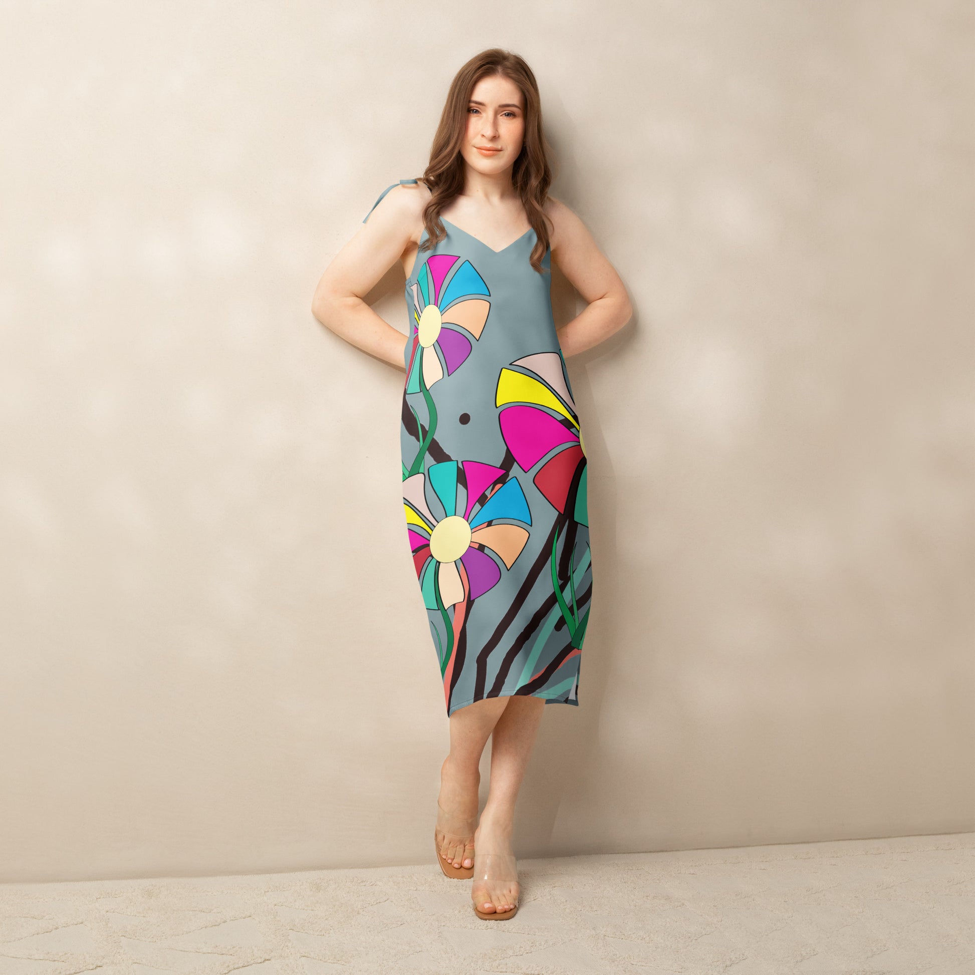 Front view of a woman modeling a v-neck, sleeveless midi dress in soft gray with large, multi-colored flower prints.