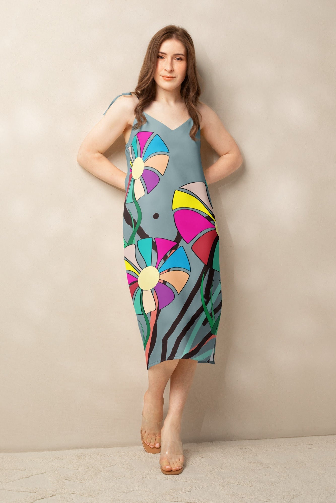 Front view of a woman modeling a v-neck, sleeveless midi dress in soft gray with large, multi-colored flower prints.