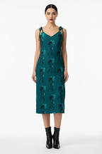 Woman wearing a teal dress with black patterns on a white background