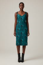 Woman wearing a teal dress with a pattern on a white background