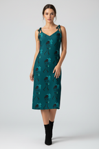 Woman wearing a teal dress with floral pattern on a white background