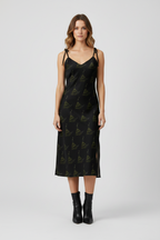 Woman wearing a black slip dress with a subtle pattern on a white background