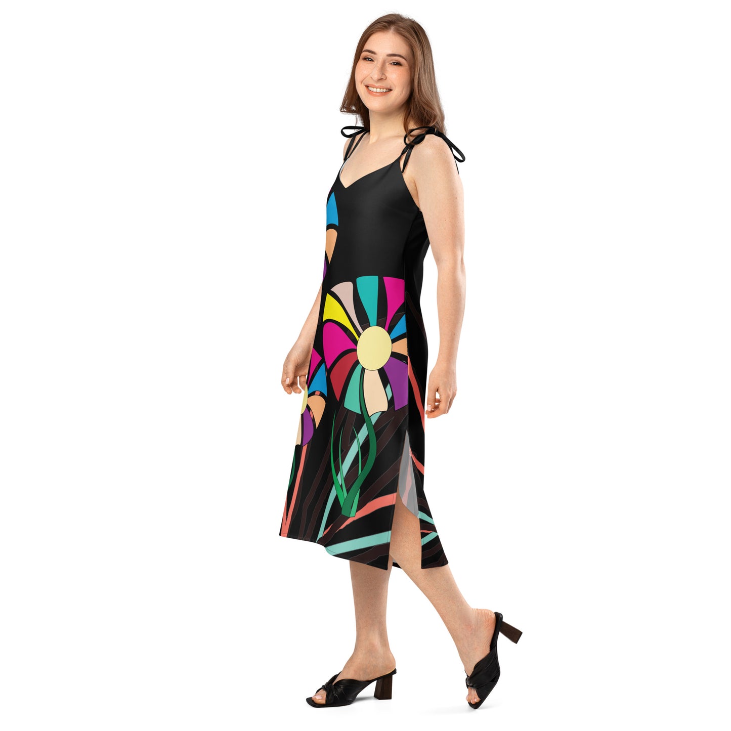 Full-length view of a woman wearing a green midi dress with a colorful abstract floral pattern, featuring tie straps and a high side slit.