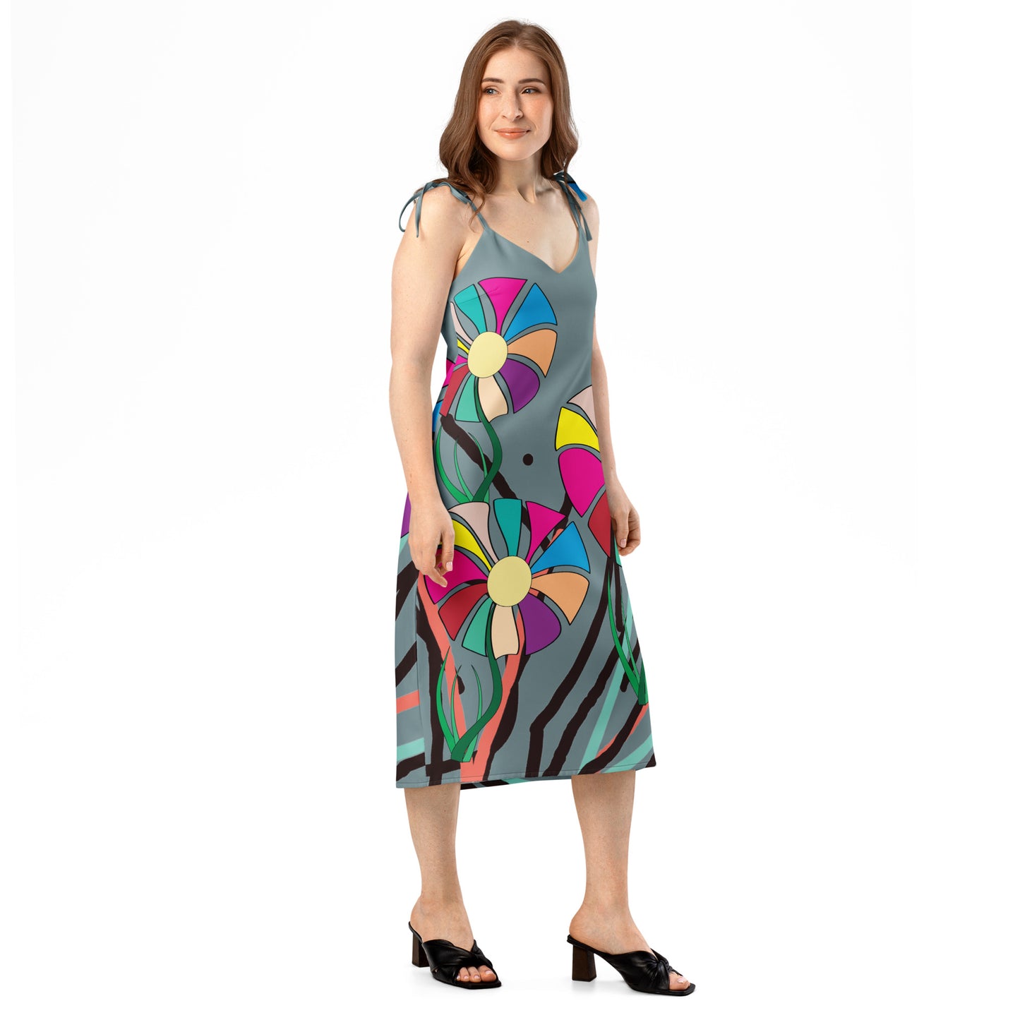 Full-length view of a woman wearing a gray midi dress with a colorful abstract floral pattern, featuring tie straps and a high side slit.