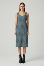 Woman wearing a blue dress with sailboat pattern on a white background