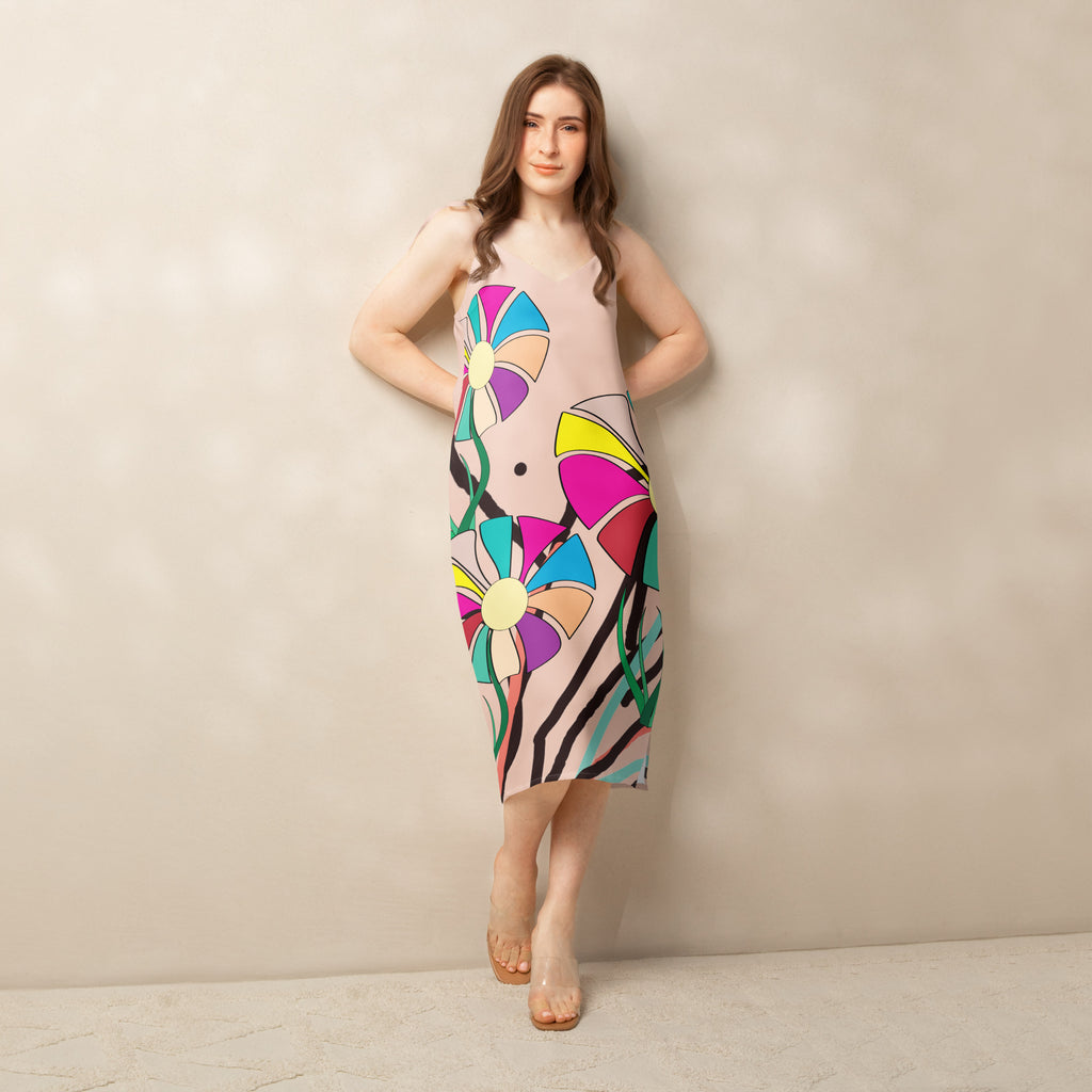 A woman modeling a sleeveless midi dress with a colorful abstract floral print on a light beige background.