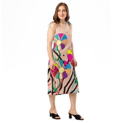 Full-length view of a peach midi dress with a colorful abstract floral pattern, featuring tie straps and a subtle side slit.