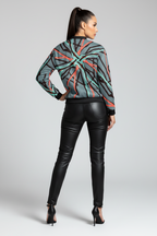 Woman wearing a patterned sweater and black leather pants on a gray background