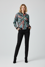 Woman wearing a patterned shirt and black pants on a white background