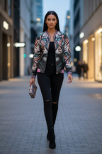 Woman walking on a city street wearing a colorful jacket and black pants.