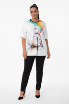 Woman wearing a white t-shirt with a colorful graphic design and black pants on a white background