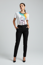 Woman wearing a white t-shirt with a colorful graphic design and black pants on a gray background