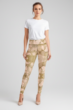 A woman modeling high-waisted leggings with an abstract geometric pattern in beige, tan, and olive green, paired with a plain white t-shirt and nude heels, against a light gray studio background.