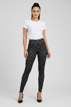 Woman wearing a white t-shirt and black patterned leggings on a gray background