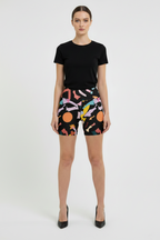 Woman wearing black t-shirt and colorful patterned shorts on a white background