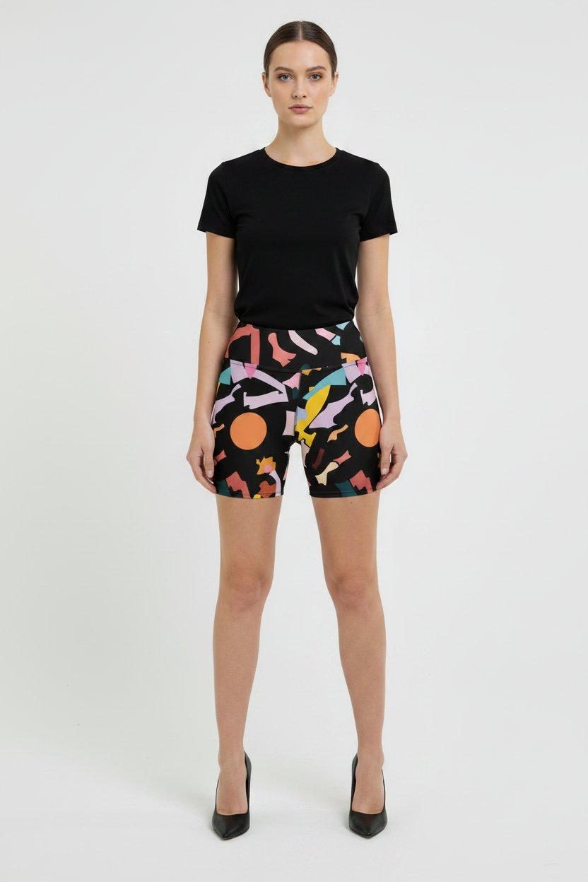 Woman wearing black t-shirt and colorful patterned shorts on a white background