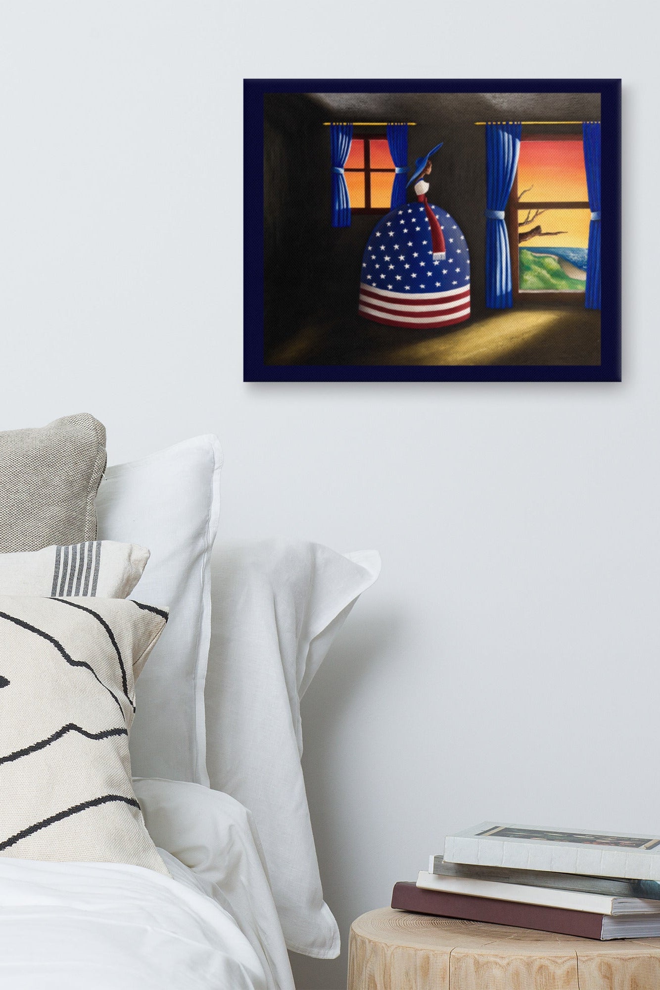 A framed art print hanging on a light gray wall above a bed. The print shows a surreal painting of a person in a blue bonnet with an American flag pattern, standing in a dark room with windows showing a sunset.