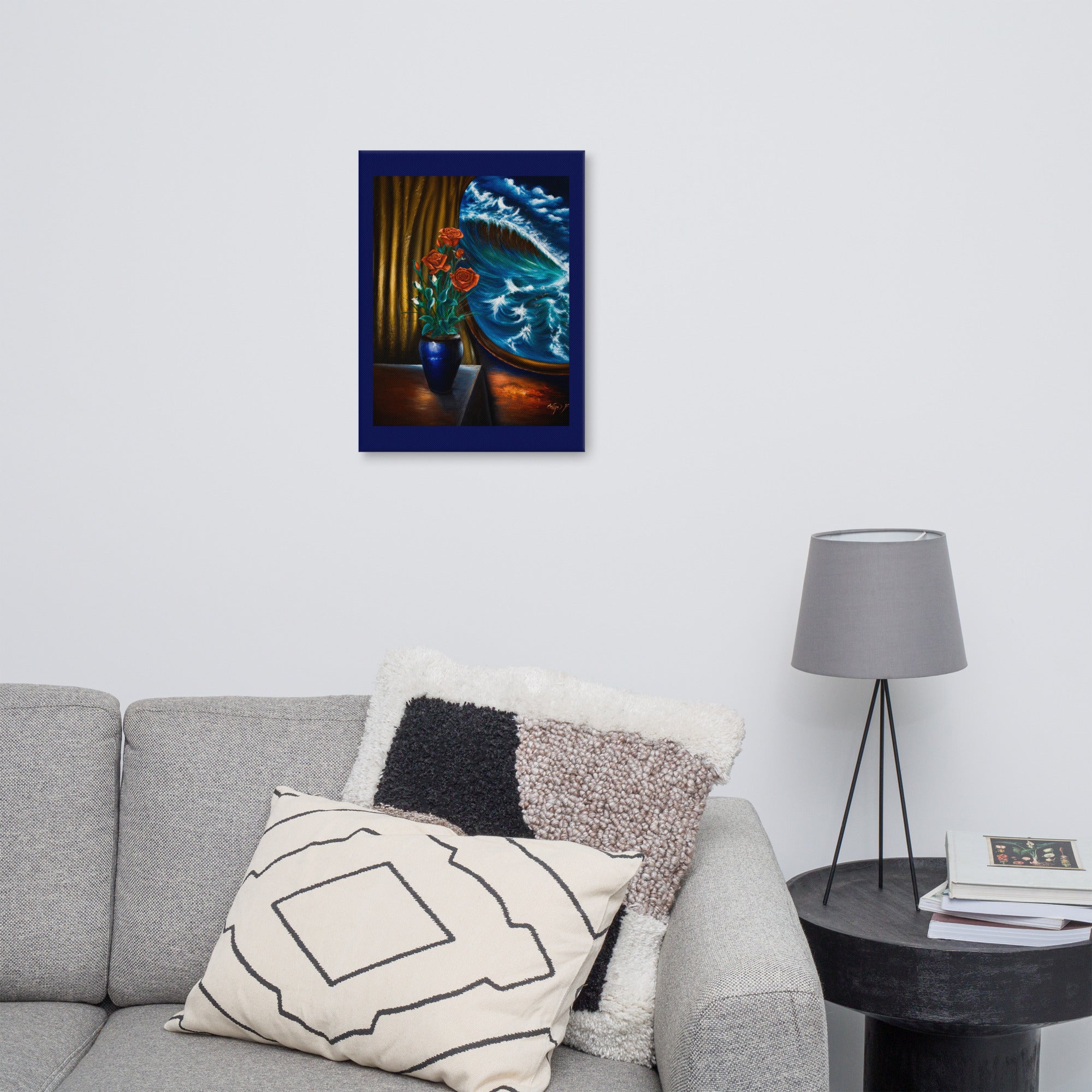A framed vertical canvas print of a dramatic oil painting featuring a shark in blue water and red flowers, displayed on a light gray wall above a modern gray sofa with decorative pillows and a side table with a lamp.