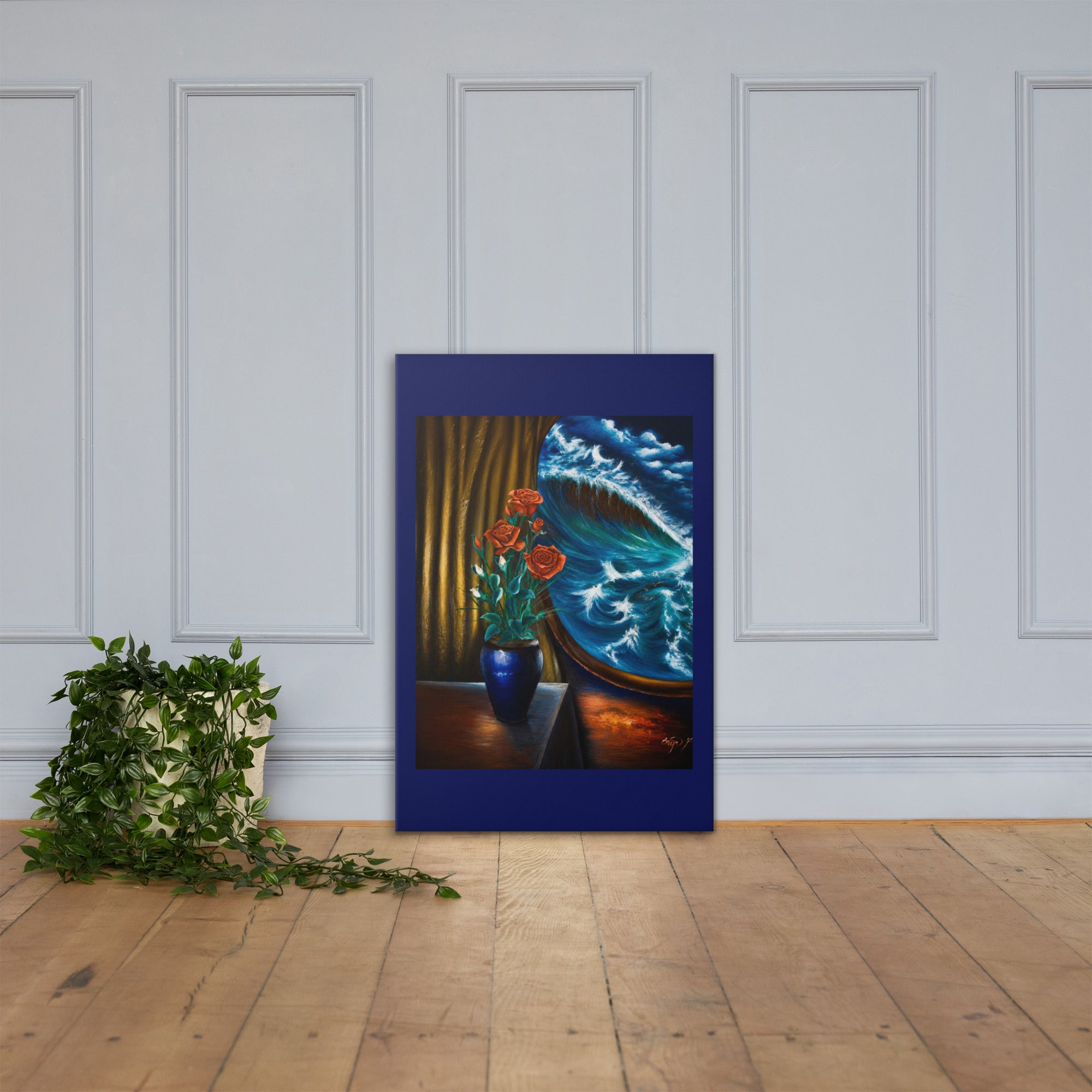 A framed art print leaning against a white paneled wall on a light wood floor, next to a green trailing plant. The artwork features a dark blue border and depicts a still life with red flowers in a blue vase, gold curtains, and a blue-and-white wave pattern.