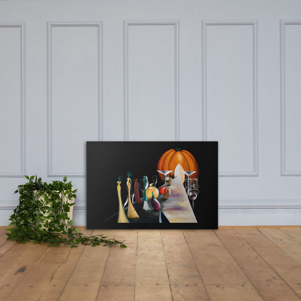 A framed abstract still life canvas print leaning against a white paneled wall on a light wood floor, with a potted green plant to the left. The artwork features a black background, a bright orange pumpkin, and stylized figures and objects in muted tones.