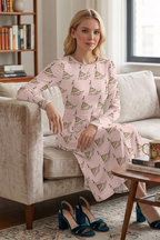 Woman in a pink patterned dress sitting on a beige sofa in a cozy living room.