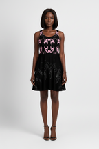 Woman wearing a black dress with pink floral patterns on a white background