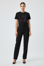 Woman wearing a black t-shirt with a graphic design and black pants on a white background