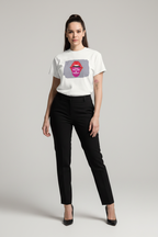 A woman modeling a white short-sleeve graphic T-shirt with a gray square print featuring red lips and the text 'DON'T BE A IDOL', paired with black trousers and black heels, against a light gray studio background.