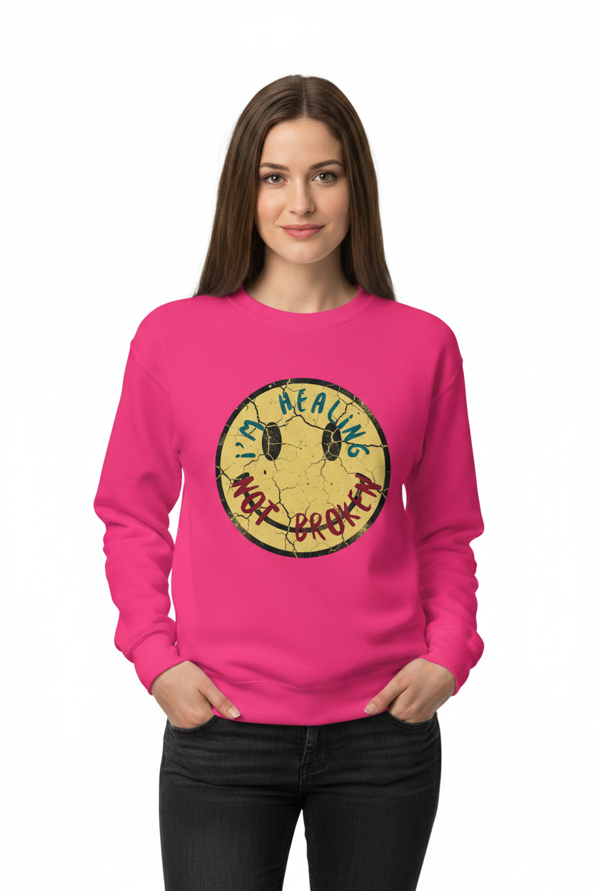 Woman wearing a pink sweatshirt with a smiley face graphic and text.