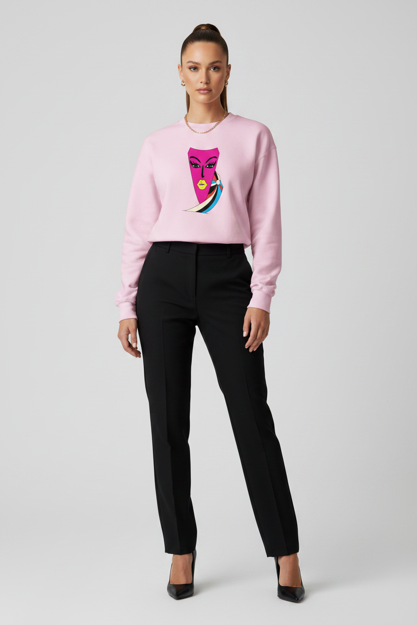 Woman wearing a pink sweater with a colorful design and black pants on a light gray background