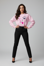 Woman wearing a pink sweatshirt with a graphic design on a gray background