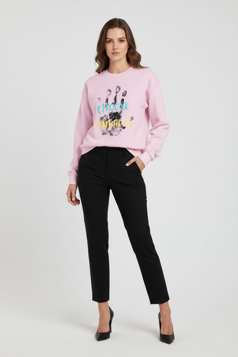 Woman wearing a pink sweatshirt with colorful text and black pants on a white background